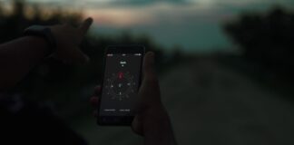 Myśliwy korzystający z kompasu w smartfonie o zmierzchu na łowisku